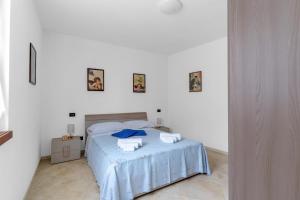 a white bedroom with a bed with blue sheets at Casa della Regina, near Lake Garda in Montichiari