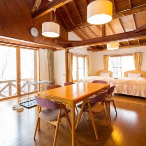 ein Esszimmer mit einem Tisch und ein Schlafzimmer in der Unterkunft Tateshina Wan-Wan Paradise Cottage in Tateshina