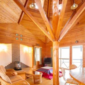 ein Wohnzimmer mit einer hohen Holzdecke und einem Bett in der Unterkunft Tateshina Wan-Wan Paradise Cottage in Tateshina