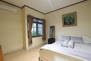 a bedroom with a large white bed and a window at Imah Budi Luhur in Bandung