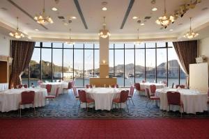 尾道市にあるGreen Hill Hotel Onomichiのテーブルと椅子、大きな窓のある宴会場