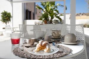 einen Tisch mit einem Teller mit einem Croissant drauf in der Unterkunft Nesea Bed and Breakfast in San Vito lo Capo