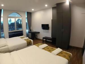 a hotel room with two beds and a television at HOTEL KAWAN BIDOR in Sungkai
