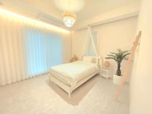 a white bedroom with a bed and a potted plant at La Solis in Incheon