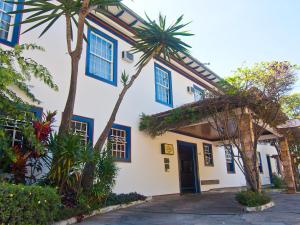 a building with blue shuttered windows and palm trees at Pousada do Garimpo in Diamantina