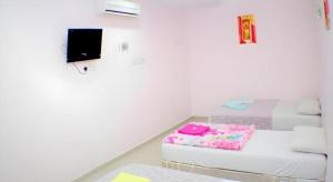 a white room with a bed and a tv at Taipann Hotel in Kampong Telok Gadong Besar