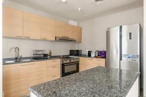 a kitchen with wooden cabinets and a stainless steel refrigerator at Silkhaus Luxury 2BR Stay in Reem Island Sigma II in Abu Dhabi