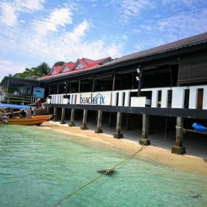a boat in the water in front of a building at Beach Box Perhentian in Perhentian Island