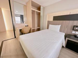 a bedroom with a large white bed and a desk at โรงแรม โอทู แกรนด์ สุวรรณภูมิ แอร์พอร์ต in Bang Phli