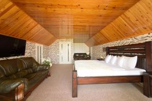 a bedroom with a bed and a leather couch at Brestinlove: Rodnikovyj Guest House in Brest