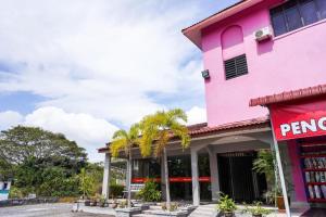 a pink building with palm trees in front of it at OYO 89643 S.s Motel in Pantai Cenang