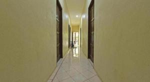 an empty hallway with brown doors and a tile floor at OYO 90596 Casaria Inn in Kampong Baru