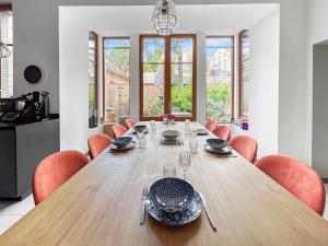 a dining room with a wooden table and orange chairs at Grand T4 Luxe, SPA, Cheminée Baby-foot, Jardin in Aix-les-Bains