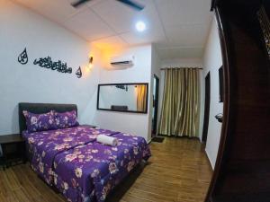 a bedroom with a purple bed in a room at Roomstay Pondok Aboh in Setiu
