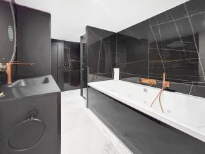 a black bathroom with a tub and a sink at Grand T4 Luxe, SPA, Cheminée Baby-foot, Jardin in Aix-les-Bains +40 photos