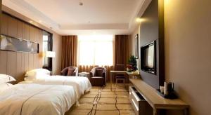 a hotel room with a bed and a flat screen tv at Century Land Hotel Wuyishan in Wuyishan