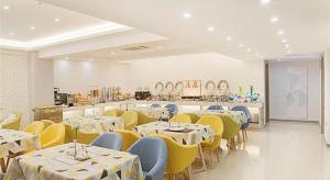 a restaurant with white tables and yellow chairs at Borrman Hotel Zhenjiang Dashikou Suning Plaza in Zhenjiang