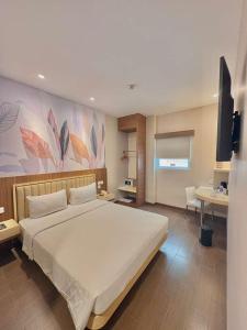 a bedroom with a large white bed and a desk at Alltrue Lite Hotel Nagoya Hill Batam in Nagoya