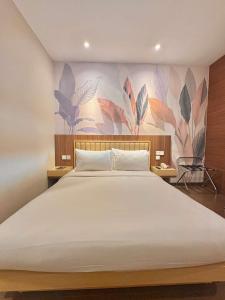 a bedroom with a large white bed with a floral wall at Alltrue Lite Hotel Nagoya Hill Batam in Nagoya
