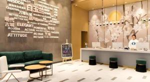 a lobby with a green couch and a counter at Magnotel Huludao Xingcheng Central Square Wenquan Street in Huludao