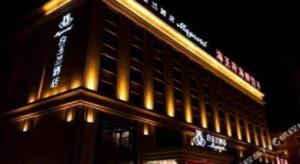 a tall building with a sign on top of it at Magnotel Huludao Xingcheng Central Square Wenquan Street in Huludao