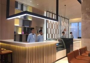 two men standing at a bar in a restaurant at Echarm Hotel Taizhou International Convention and Exhibition Center 