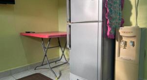 a kitchen with a red table next to a refrigerator at OYO 90967 Homestay Chalet Warisan Siti in Pulau Langkawi