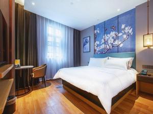a bedroom with a large bed and a table with a chair at Jinjiang Inn Wuhan Linjiaohu Wanda Branch in Wuhan +242 photos