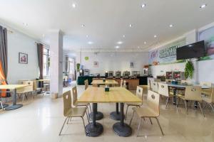 a restaurant with tables and chairs in a cafeteria at GreenTree Inn Yancheng Dongtai West Wanghai Road Shell Hotel in Dongtai