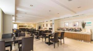 un restaurante con mesas y sillas negras y un bar en Jinjiang Inn Central Changshu Yushan, en Changshu