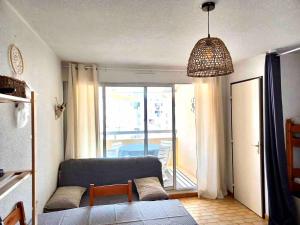 un salon avec un canapé et une grande fenêtre dans l'établissement Grau du Roi Appartement proche de la mer, au Grau-du-Roi