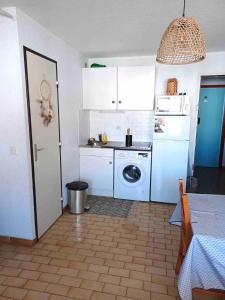 une cuisine avec des armoires blanches et une machine à laver dans l'établissement Grau du Roi Appartement proche de la mer, au Grau-du-Roi