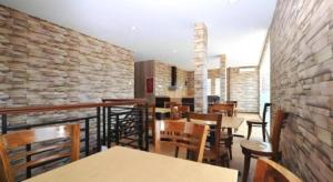 a restaurant with tables and chairs and a brick wall at Amaya Suites Hotel in Yogyakarta +77 photos