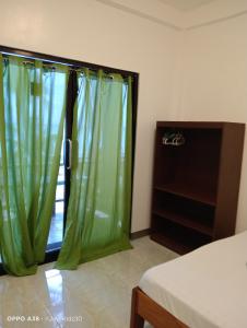 a bedroom with a window with green curtains at Lapyahan Guest House Room 5 in Lalao +9 photos