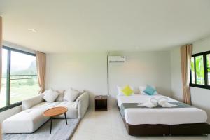 ein Wohnzimmer mit zwei Betten und einer Couch in der Unterkunft Khaosok River Stone Resort & Camp in Ban Thung Lang Tham