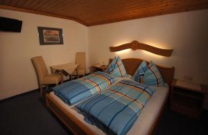 a bedroom with a bed with blue pillows and a table at Gästehaus Aigner in Saalbach-Hinterglemm