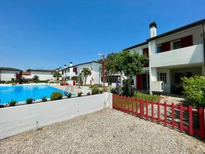 a house with a fence next to a swimming pool at Terraced house with garden and pool in Porto Santa Margherita di Caorle