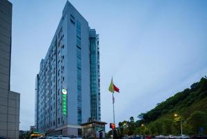 un grand bâtiment avec un drapeau devant lui dans l'établissement GreenTree Inn JinDeZhen People Square Taoxichuan Wenchuang Street, à Jingdezhen