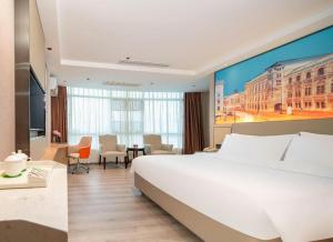 東莞市にあるVienna 3 Best Hotel Dongguan Liaobu Shida Roadの大きな白いベッドと机があるホテルの部屋