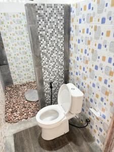 a bathroom with a toilet with a mosaic wall at AMED LILI Private Room in Amed