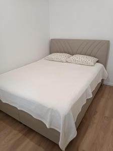 Una cama con sábanas blancas y almohadas. en Il sogno apartman, en Vranješ