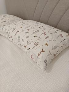 almohada con motivos florales en la cama en Il sogno apartman, en Vranješ