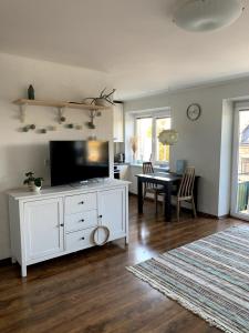 una sala de estar con un centro de entretenimiento blanco con TV en Bright and cozy apartment in the city center with balcony, en Šiauliai