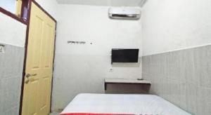 a small room with a bed and a television at Hotel O Benteng Kost in Jambi