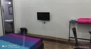 a living room with a table and a tv on a wall at BENUTHOMESTAY in Kampong Parit Tengah