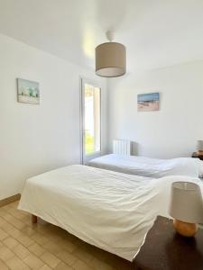a white bedroom with two beds and a window at Maison familiale 3 chambres proche de la plage, jardin & tranquillité in Saint-Denis-dʼOléron