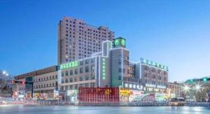a large building with neon signs in a city at GreenTree Inn Geermu Walking Street Business Hotel in Golmud
