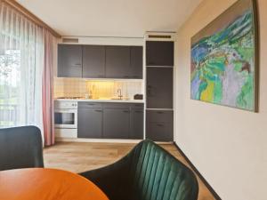 a kitchen with black cabinets and a green chair at Hotel Aeschi Interlaken - Handwritten Collection in Aeschi