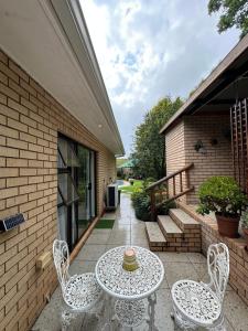 un patio con una mesa y 2 sillas y una escalera en Clivia Guesthouse, en Pietermaritzburg