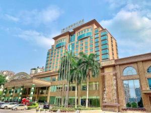 a building with palm trees in front of it at Riverside International Hotel in Wuzhou